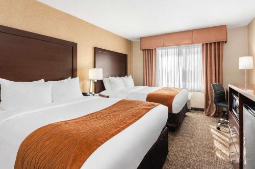 バンクーバーにあるComfort Inn & Suites Vancouver Downtown City Centerのベッド2台とデスクが備わるホテルルームです。