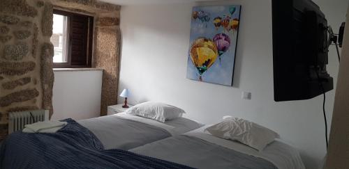 uma cama com lençóis brancos e almofadas num quarto em Casa Dr. Saba em Belmonte