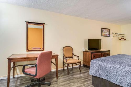 a room with a desk and a bed and a television at Econo Lodge At Six Flags in Austell