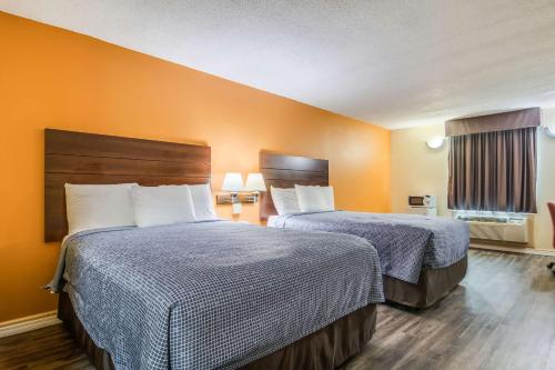 two beds in a hotel room with orange walls at Econo Lodge At Six Flags in Austell