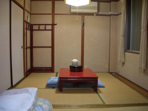 Kasuga Ryokan في هيروشيما: غرفة مع طاولة في منتصف الغرفة