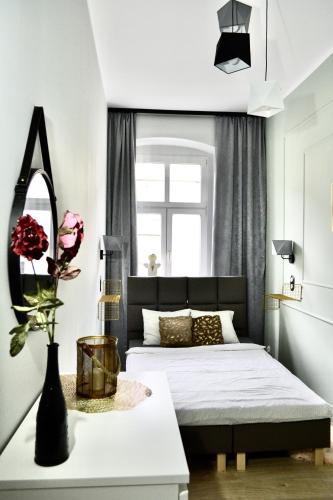 a bedroom with a bed and a table with a vase of flowers at Angel Apartment Taczaka in Poznań