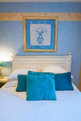 a bed with blue walls and a picture above it at Hotel Relais Du Postillon in Antibes