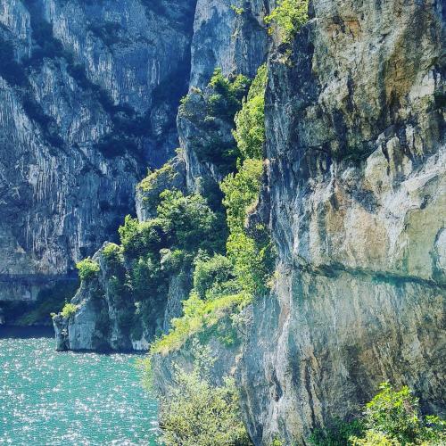 a rocky mountain with trees on it next to a body of water at CASA DELLE API in Pisogne
