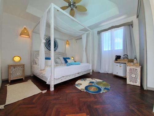 a bedroom with a white canopy bed and a wooden floor at Au Temps D'antan- Ile Rodrigues in Rodrigues Island