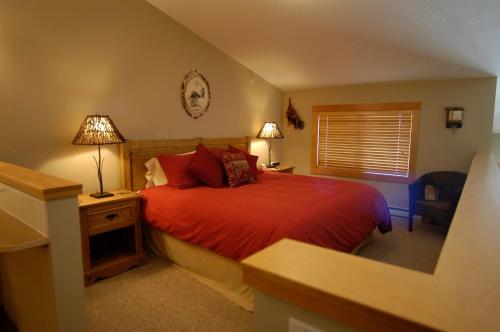 1 dormitorio con cama roja, escritorio y lámpara en Apartment 406, Indigenous Artefacts, en Canmore