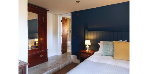 Un dormitorio con una pared de acento azul y una cama en The Blue Ball Inn en Sidmouth