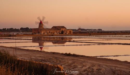 a building with a windmill in the middle of a field at La Vie En Rose in Marsala
