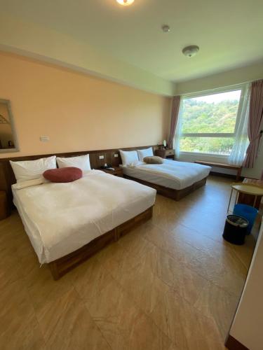 a bedroom with two beds and a large window at DooDoo B&B in Jiji