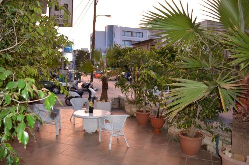 un patio con mesa, sillas y plantas en Lefka Ori City Rooms, en La Canea