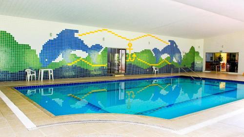 a swimming pool with a mural on the wall at Ózera Hotel Fazenda in Prudentópolis