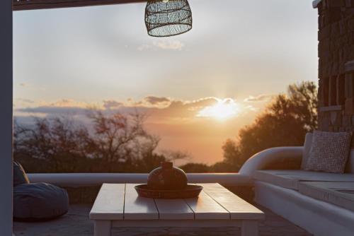 a table on a patio with a sunset in the background at Villa Tzikides Aegina in Tzíkidhes