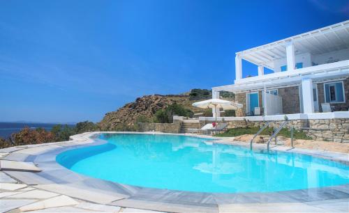 a swimming pool in front of a house at Adikri Villas & Suites in Tourlos