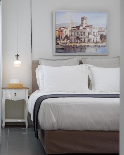 a bedroom with a bed with a painting on the wall at Villa Tzikides Aegina in Tzíkidhes