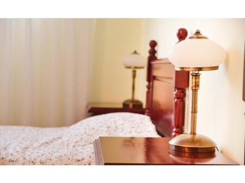 a lamp sitting on a table next to a bed at Vila Roma in Deva