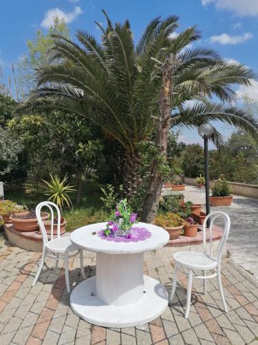 a white table and chairs with flowers on a patio at L'Isola Felice e Trulli Sotto Le Stelle in Castellana Grotte