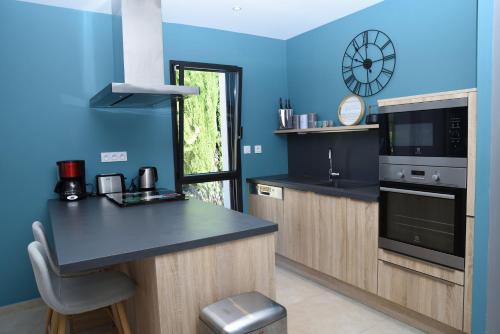 a kitchen with blue walls and a black counter top at Gite Les Lavandes in Vaison-la-Romaine