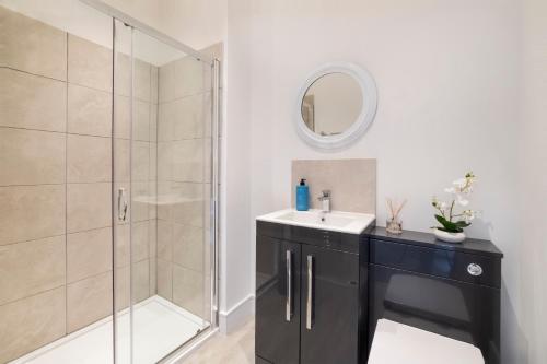 a bathroom with a shower and a sink and a mirror at Innvigour Bespoke House with Free Parking for 3 Cars in York