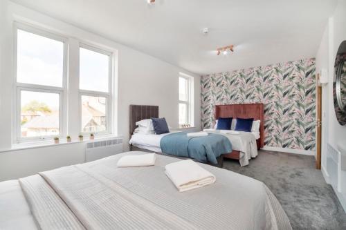 a white bedroom with two beds and two windows at Innvigour Bespoke House with Free Parking for 3 Cars in York