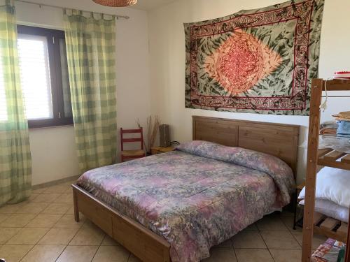 1 dormitorio con cama y alfombra en la pared en Casa Vacanza Almoraima - Salento -, en Bagnolo del Salento