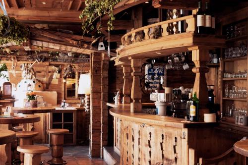 a bar in a restaurant with wooden walls and stools at Hotel Almwirt in Haar