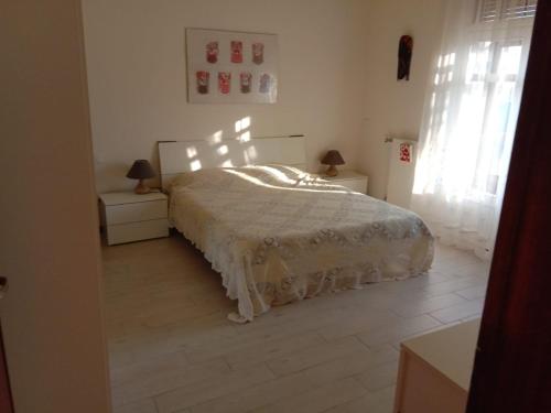 a white bedroom with a bed and two night stands at Villa Lim in Bergamo