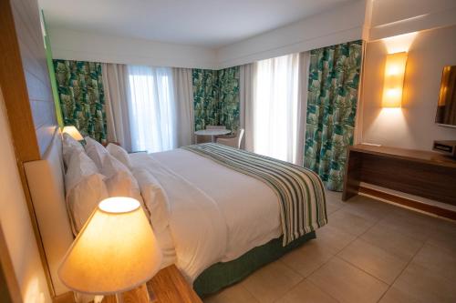 a bedroom with a large bed and a lamp at Vidam Hotel Aracaju - Transamerica Collection in Aracaju