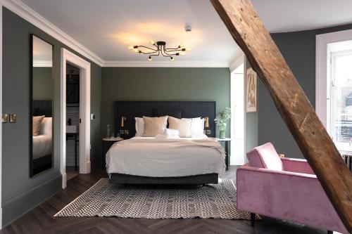 a bedroom with a large bed and a pink chair at 29 Queen Street Aparthotel in Edinburgh