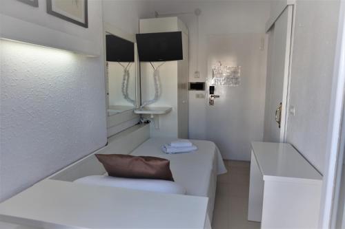 a white bathroom with a bench and a mirror at Hotel Hermes in Tossa de Mar
