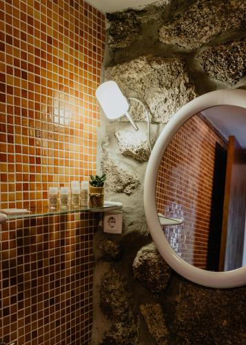 a bathroom with a mirror and a stone wall at Casas da Peneda - Geres in Gavieira