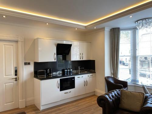 a kitchen with white cabinets and a couch in a room at The Maureen Suite in Llandudno