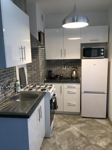 a kitchen with white cabinets and a white refrigerator at NONIEWICZA CENTRUM in Suwałki