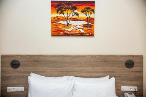 a bedroom with a bed with a painting on the wall at Silver Moon Hotel in Abidjan