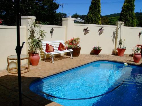a swimming pool in a patio with a bench and potted plants at DOTJJ B & B in Paarl