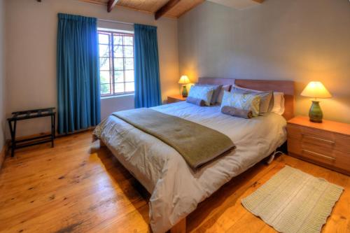 a bedroom with a large bed with blue curtains at Laragh-on-Hogsback in Hogsback