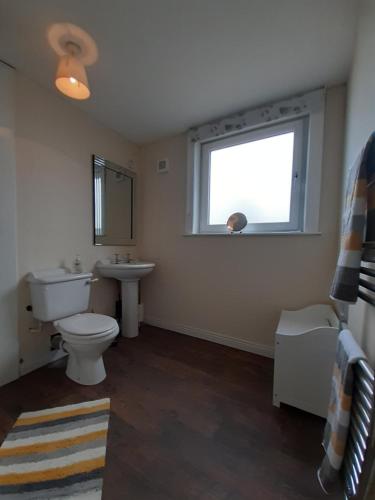 a bathroom with a toilet and a sink and a window at Carvetii - Stuart House - 1st floor flat sleeps up to 8 in Falkirk
