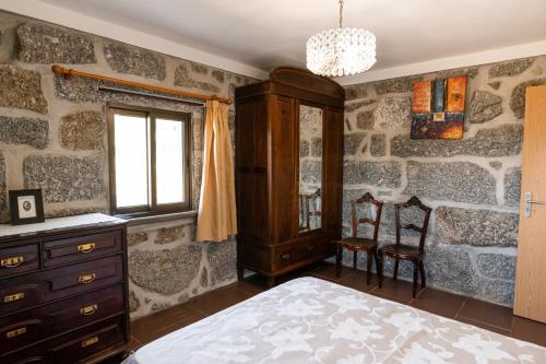 a bedroom with a stone wall with a bed and a dresser at Casa do Amial in Castelo de Paiva