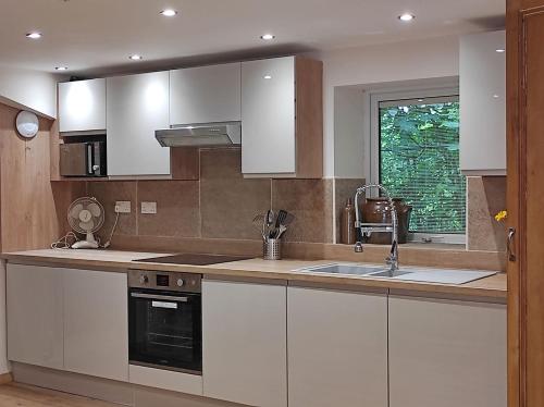 a kitchen with white cabinets and a sink and a window at Headingley Hideaway in Headingley