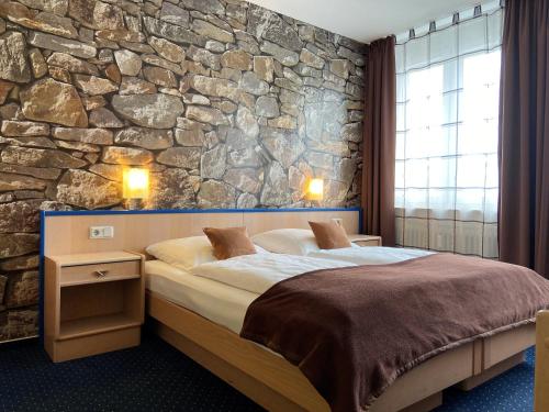 - une chambre avec un grand lit et un mur en pierre dans l'établissement Hotel Stadt Hamburg am Fluss Saarbrücken, à Sarrebruck