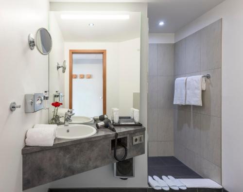 a bathroom with a sink and a mirror at Hotel Wolfsburg Centrum, Affiliated by Meliá in Wolfsburg