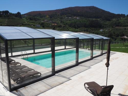 a swimming pool in a glass house with chairs at Quinta das Fontainhas in Mesão Frio