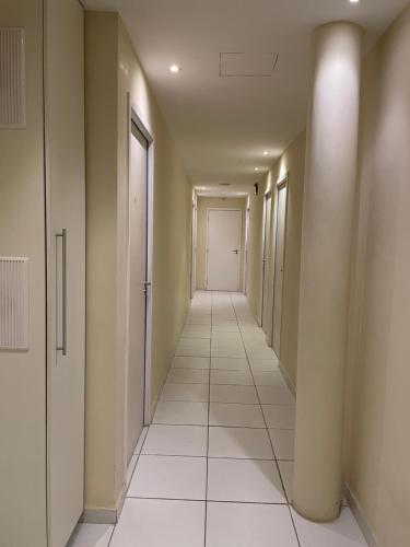 an empty hallway with white tile floors and a white door at Hotel Estação in Barueri