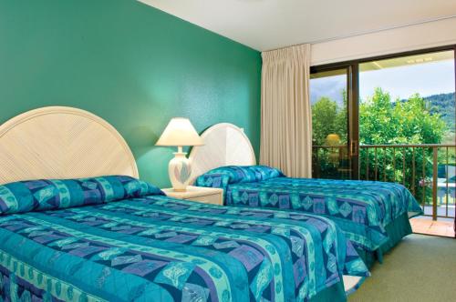 two beds in a room with a balcony at Kauai Beach Villas in Lihue