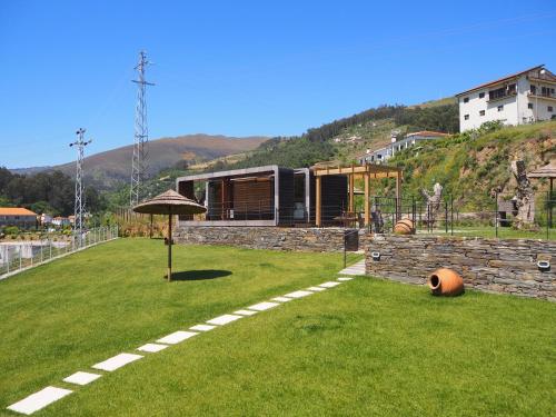 a house on a green field with an umbrella at Quinta das Fontainhas in Mesão Frio