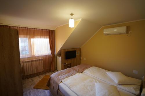 - une petite chambre avec un lit et une télévision dans l'établissement CASA FEELING, à Brădeşti