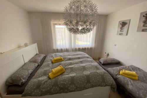 a bedroom with two beds with yellow pillows and a chandelier at Tübingen - auf dem Österberg - free parking in Tübingen