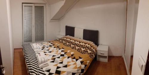 a bedroom with a bed with a black and white comforter at Apartmani Mašić Trebinje in Trebinje