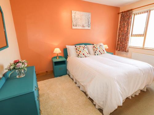 a bedroom with orange walls and a bed and a window at Ard na Gréine in Kilrean