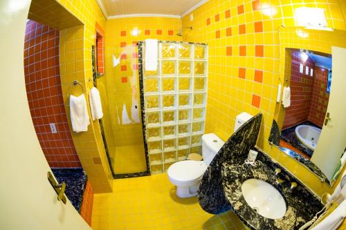 ein gelb gefliestes Bad mit einem Waschbecken und einem WC in der Unterkunft Pousada Suarez in Penedo