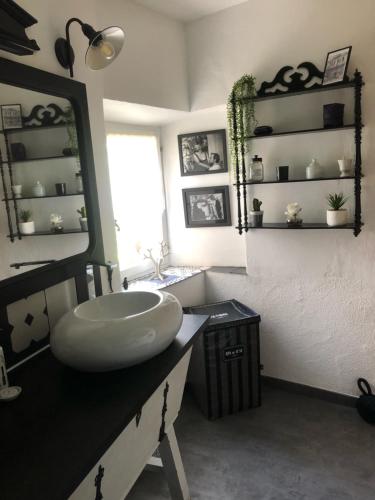 une salle de bain avec un lavabo et un grand miroir dans l'établissement Maison de village en Provence, à Baudinard